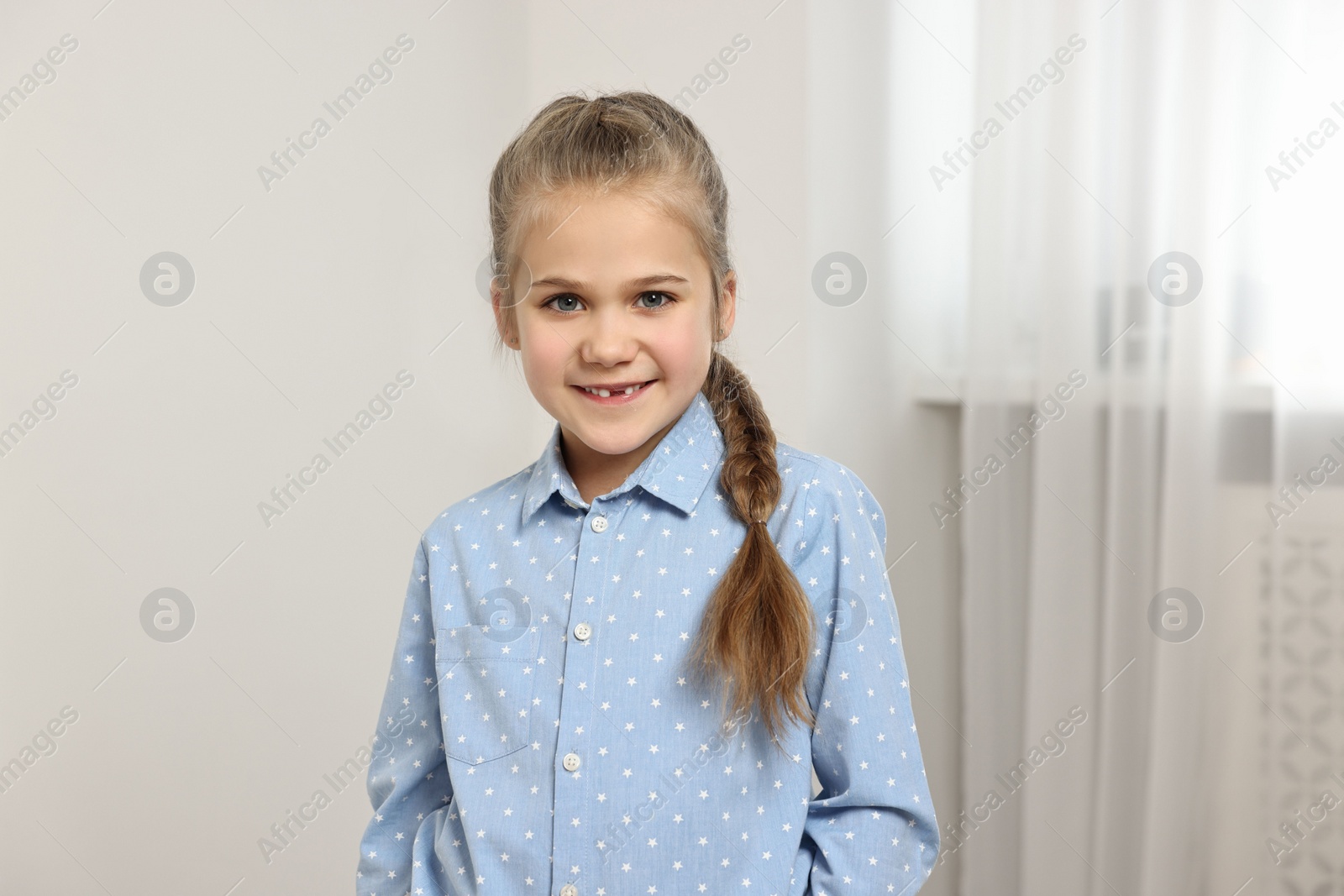 Photo of Cute little girl with braided hair indoors