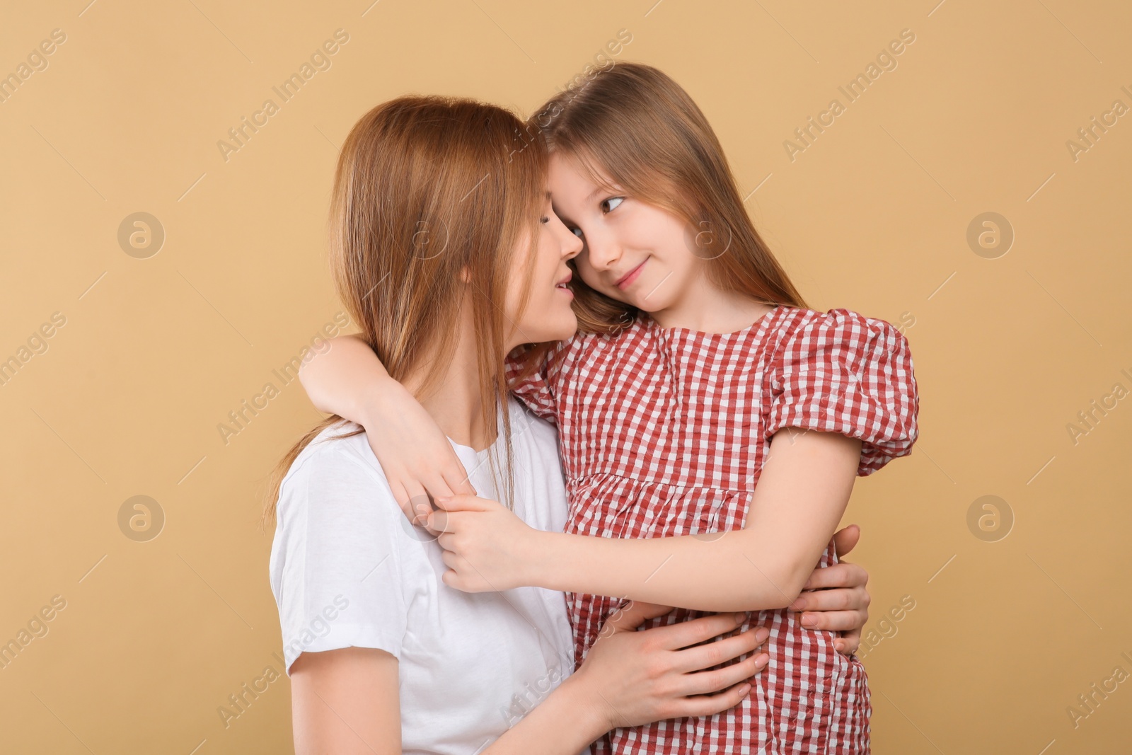 Photo of Portrait of mother and her cute daughter on beige background