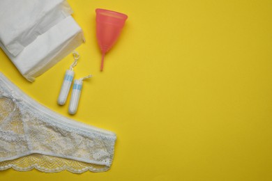 Flat lay composition with woman's panties and menstrual hygiene products on yellow background. Space for text