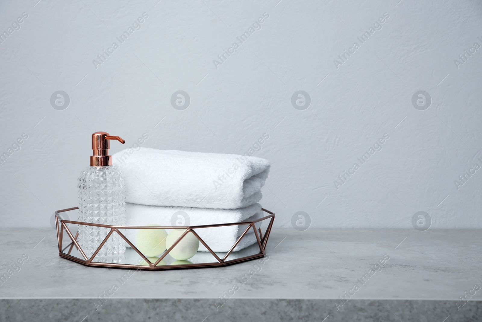 Photo of Tray with towels and toiletries on table against grey background