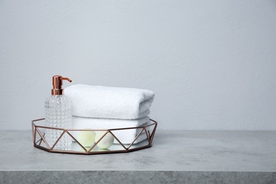 Tray with towels and toiletries on table against grey background