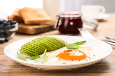 Photo of Tasty breakfast with fried egg and avocado on wooden table, closeup