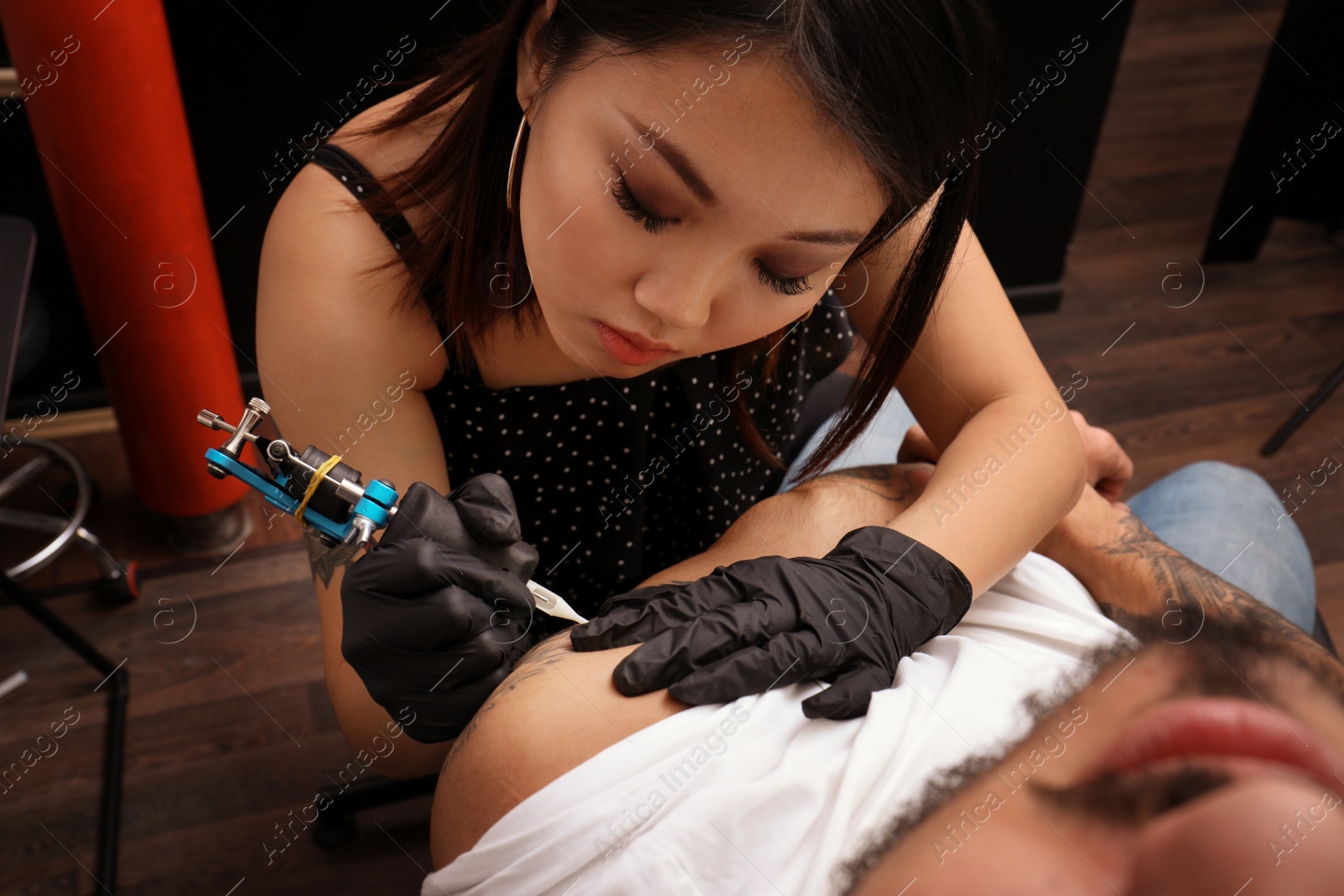 Photo of Professional artist making tattoo with machine in salon