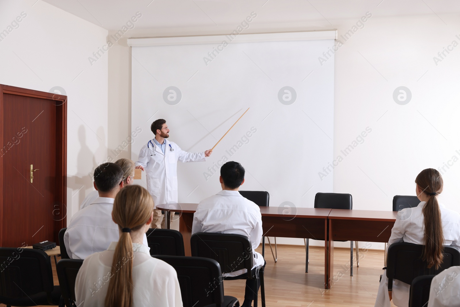 Photo of Doctor giving lecture in conference room with projection screen