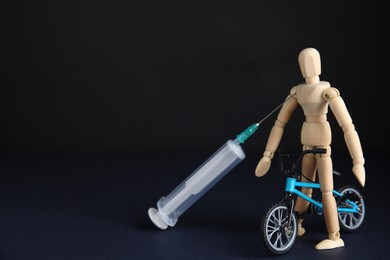 Photo of Syringe, sportsman and bike model on black background, space for text. Using doping in cycling sport concept