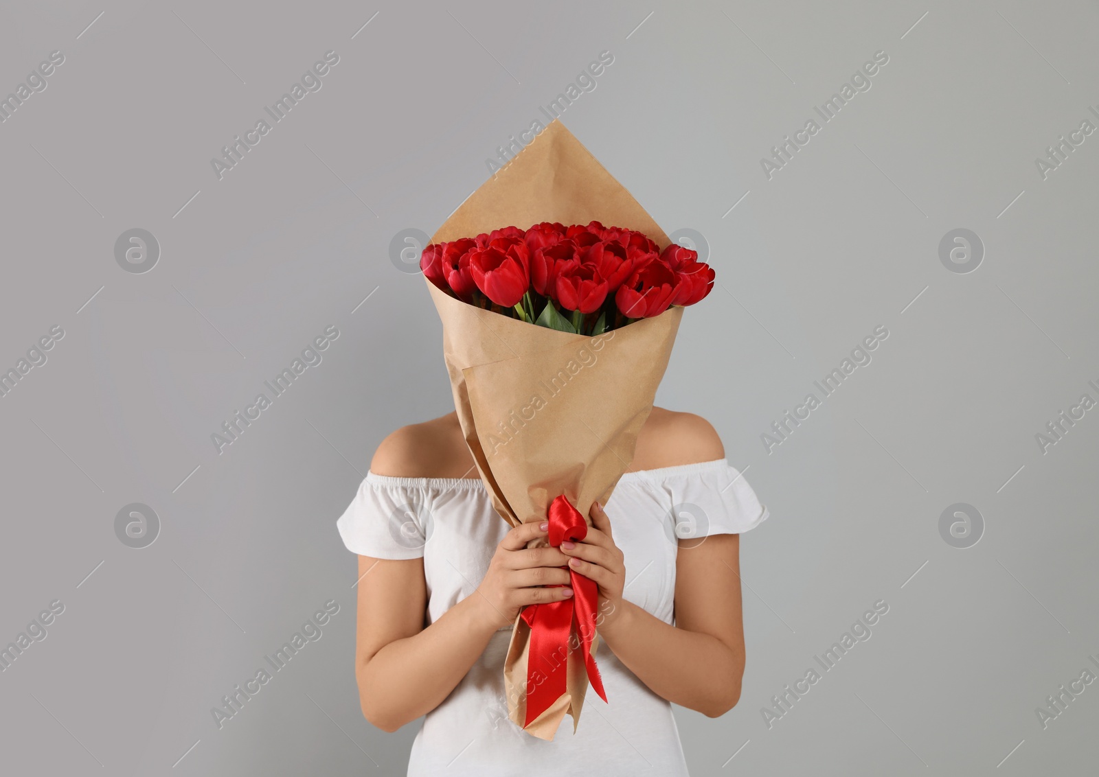 Photo of Woman with red tulip bouquet on light grey background. 8th of March celebration