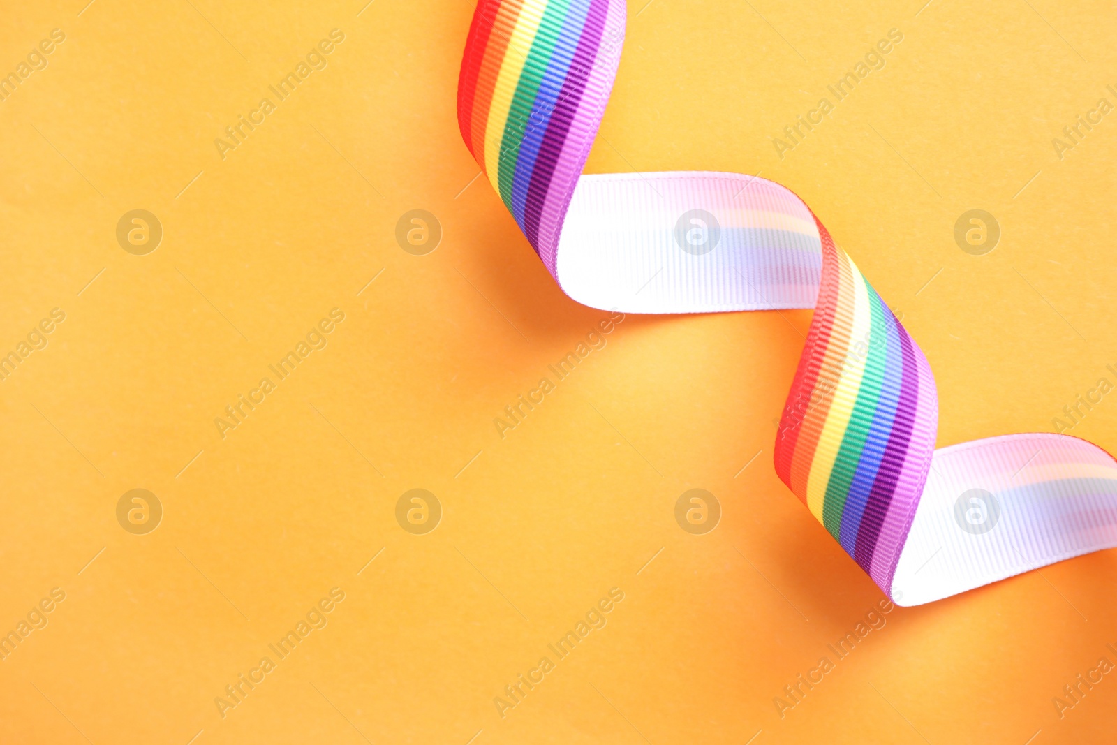 Photo of Bright rainbow ribbon on color background, top view with space for text. Symbol of gay community