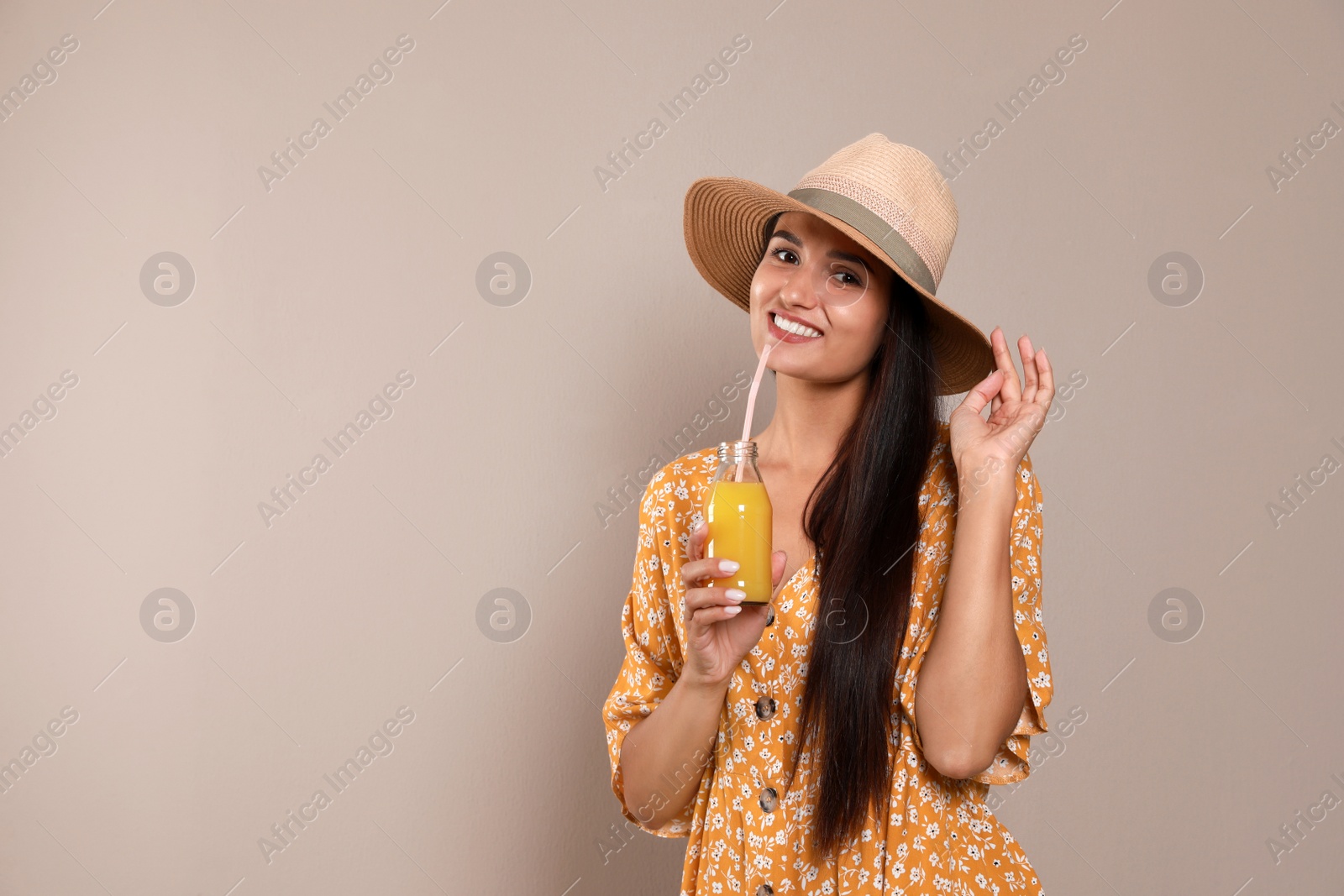 Photo of Beautiful young woman with straw hat and glass of refreshing drink on beige background. Space for text