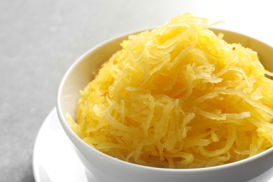 Bowl with cooked spaghetti squash on grey background, closeup