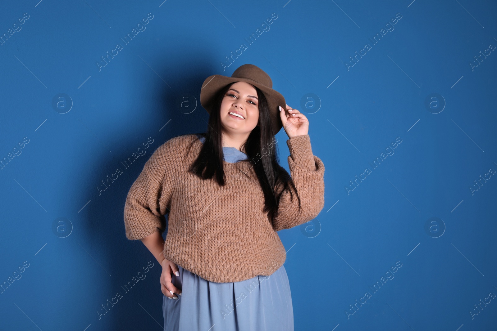 Photo of Beautiful overweight woman posing on blue background. Plus size model