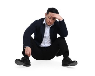 Tired businessman in suit sitting on white background