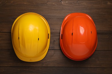Hard hats on wooden table, flat lay. Safety equipment