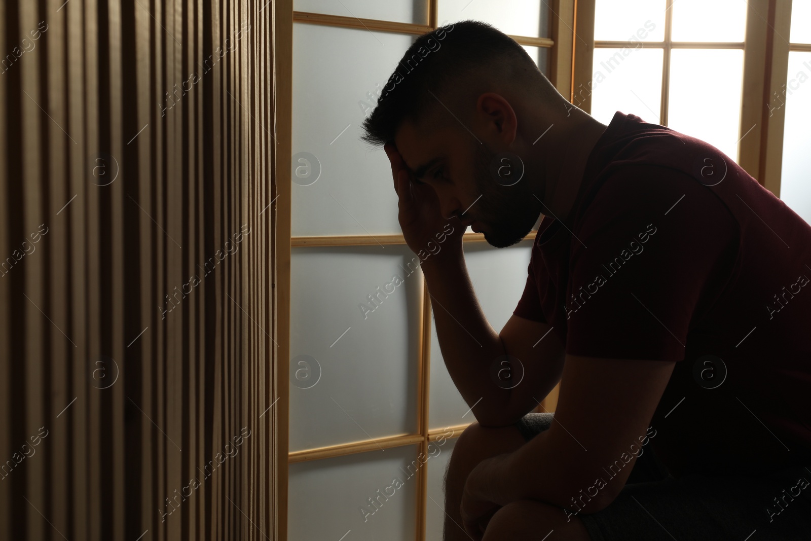 Photo of Silhouette of sad man at home. Space for text