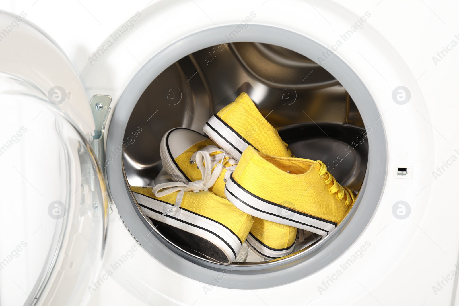 Photo of Stylish clean sneakers inside modern washing machine