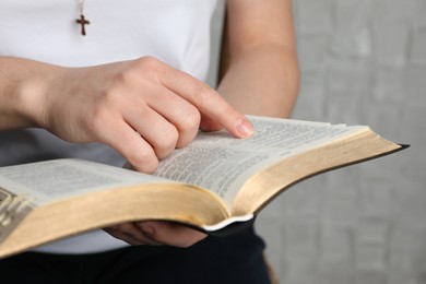 Photo of Woman reading Bible against white wall, closeup