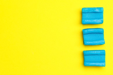 Blue bubble gums on yellow background, flat lay. Space for text