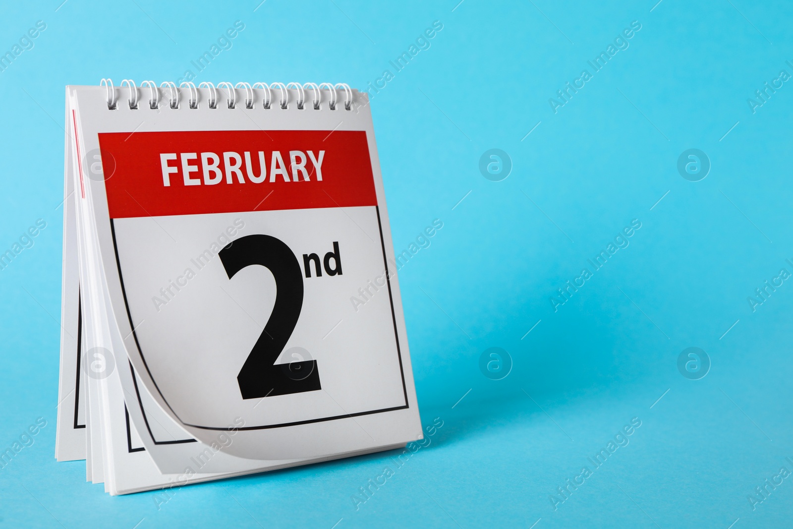 Photo of Calendar with date February 2nd on light blue background, space for text. Groundhog day