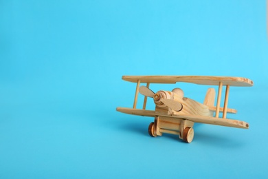 Photo of Wooden toy plane on blue background. Space for text