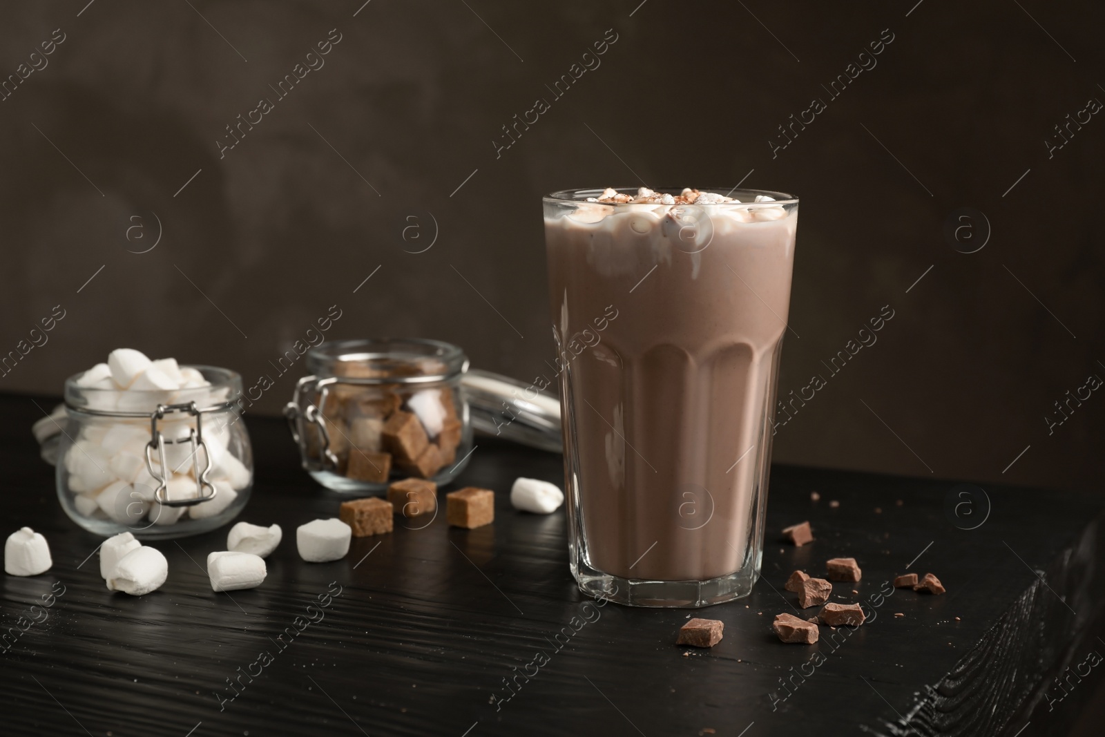 Photo of Tasty hot chocolate with milk and marshmallows in glass on table