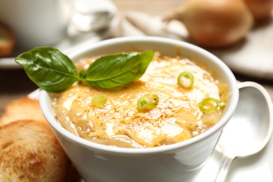 Photo of Tasty homemade french onion soup served is ceramic bowl, closeup