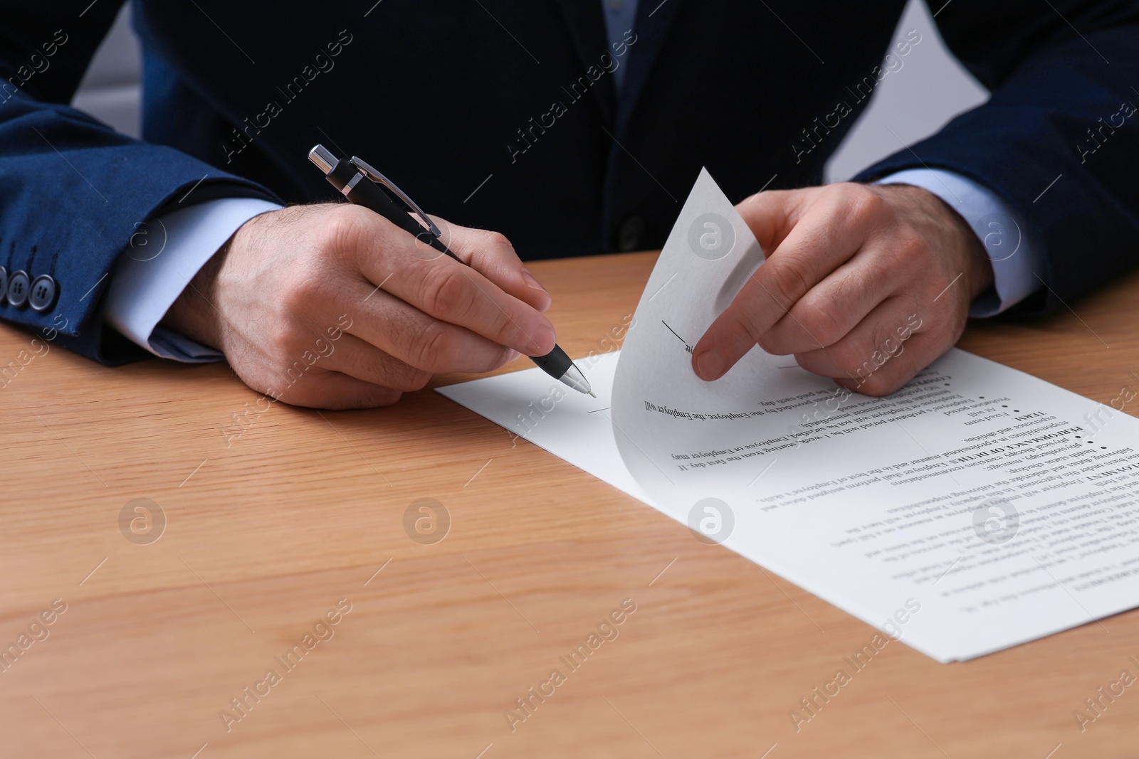 Photo of Businessman signing contract at wooden table, closeup of hands