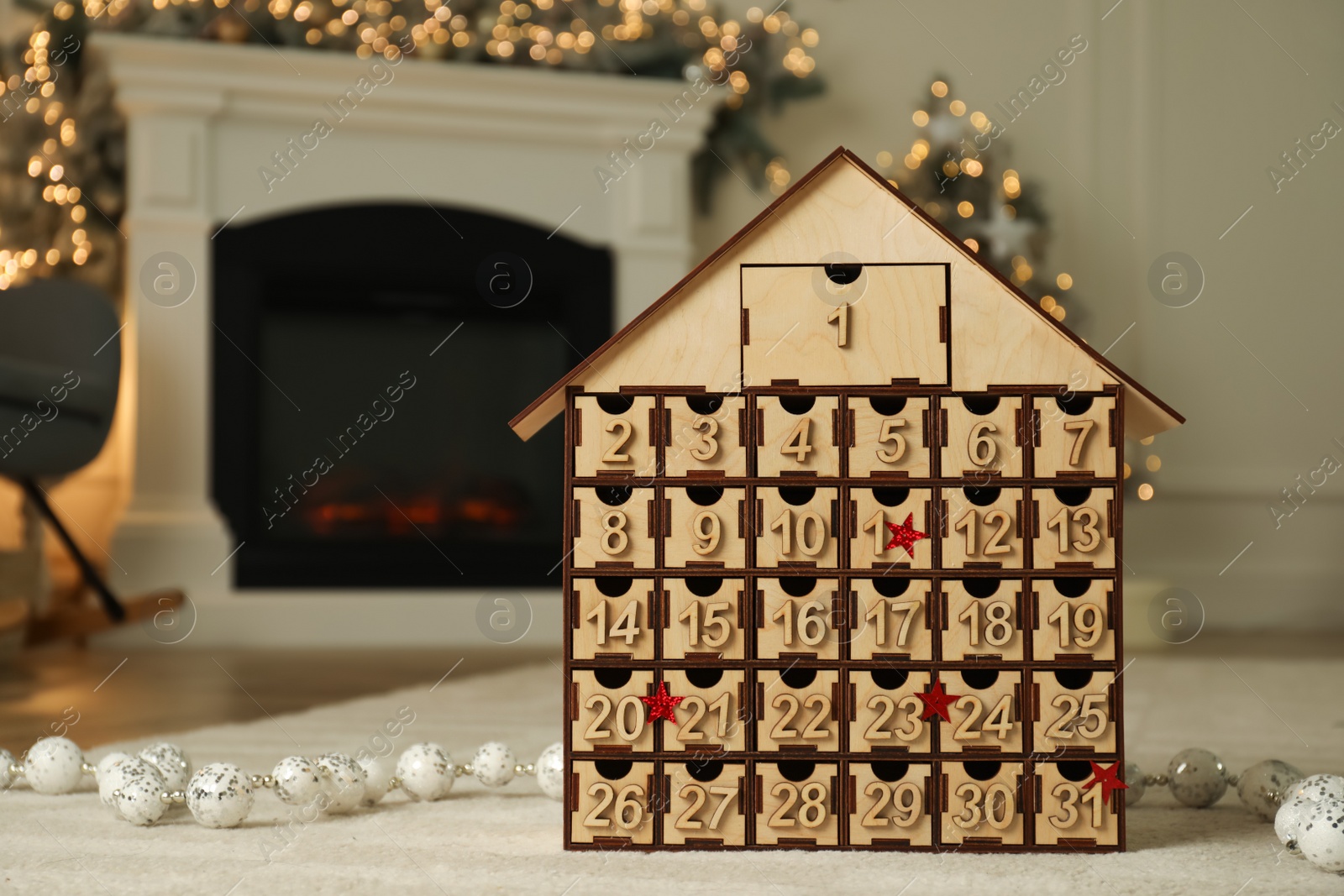 Photo of Wooden house shaped Advent calendar in room decorated for New Year, space for text