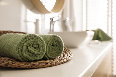 Photo of Wicker tray with clean towels on countertop in bathroom. Space for text