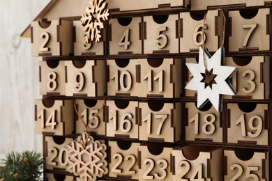 Wooden house shaped Christmas advent calendar with festive decor, closeup