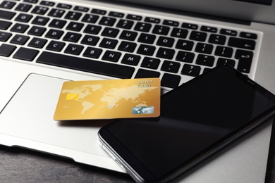 Photo of Credit card, smartphone and laptop on table, closeup