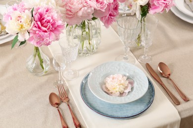 Photo of Stylish table setting with beautiful peonies and golden cutlery