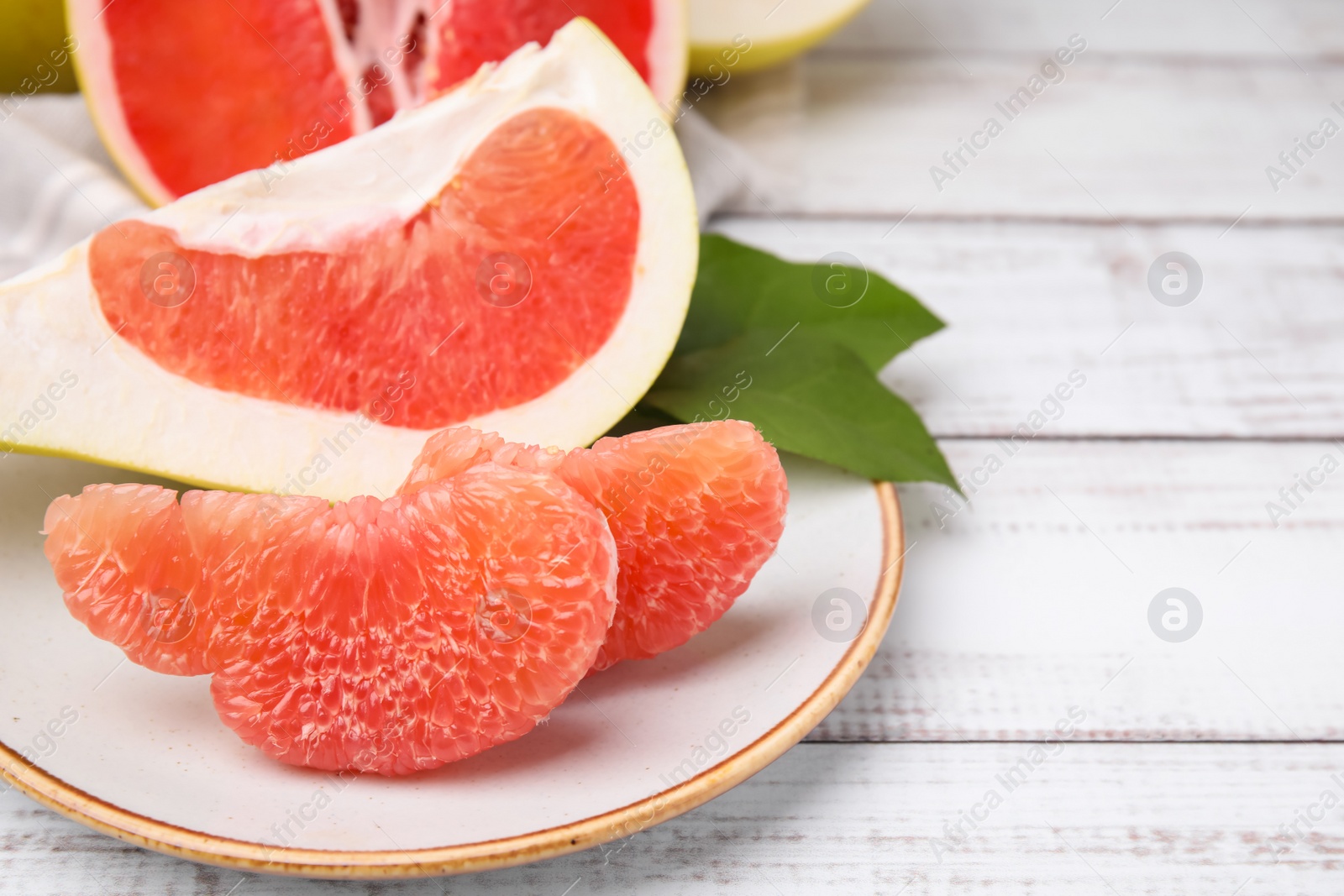 Photo of Tasty pomelo fruits on white wooden table, closeup