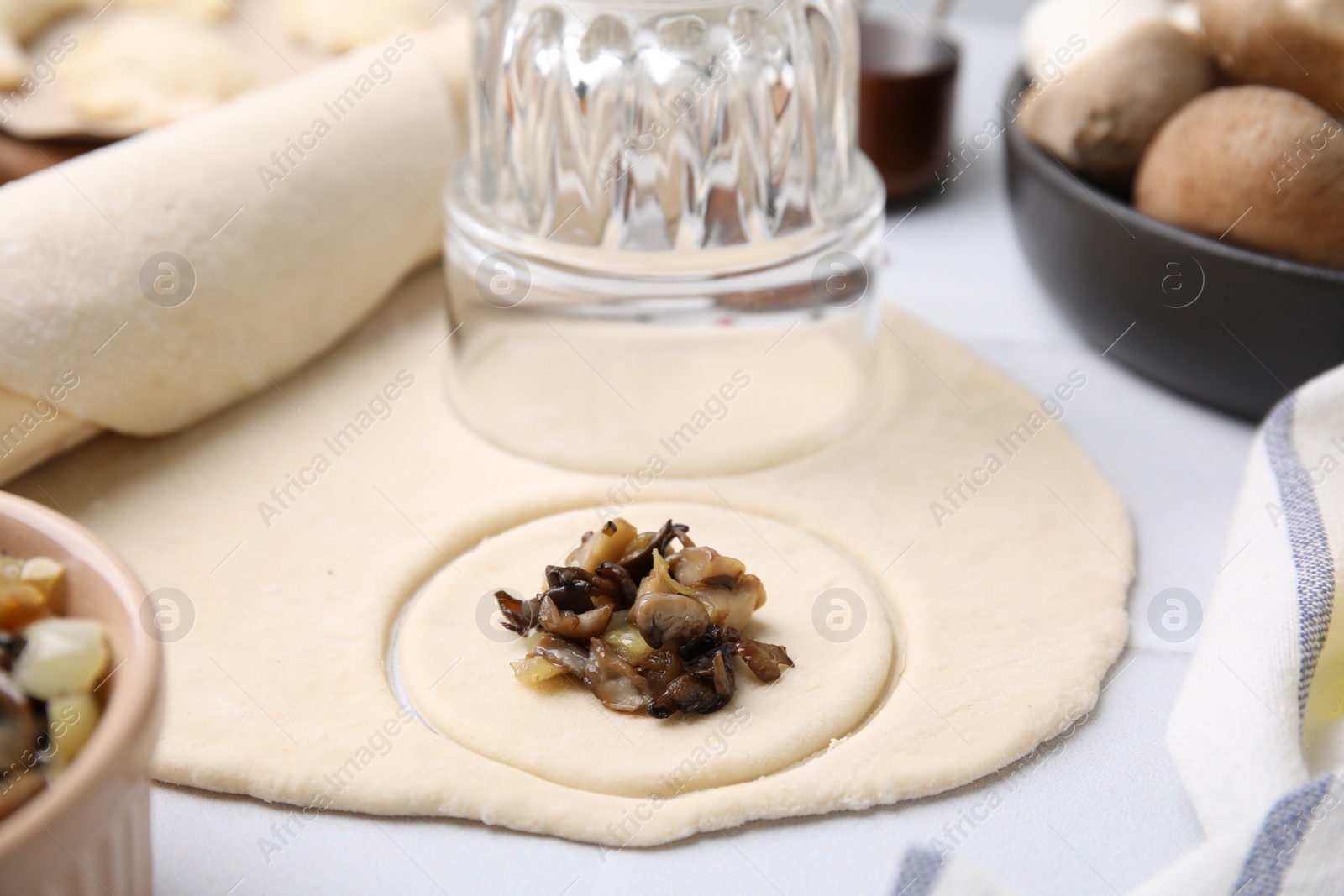 Photo of Process of making dumplings (varenyky) with mushrooms. Raw dough and ingredients on white table, closeup