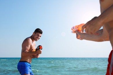 Photo of Friends with water guns having fun in sea