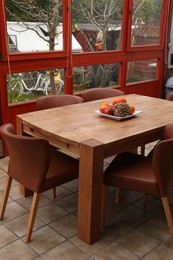 Wooden table with fruits and stylish chairs on terrace