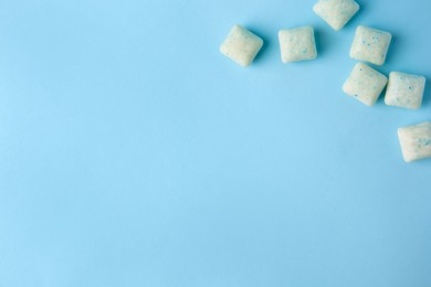 Photo of Tasty chewing gums on light blue background, flat lay. Space for text