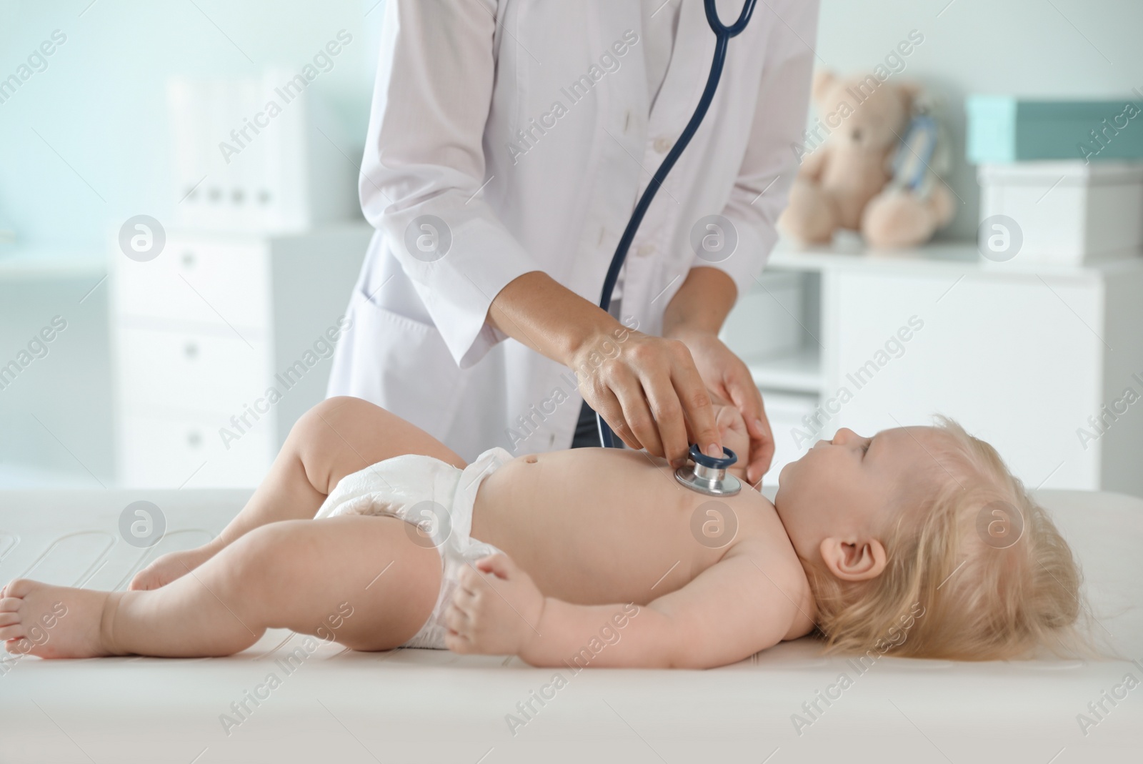 Photo of Pediatrician examining baby with stethoscope in hospital. Health care