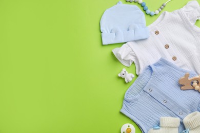 Photo of Flat lay composition with baby clothes and accessories on green background, space for text