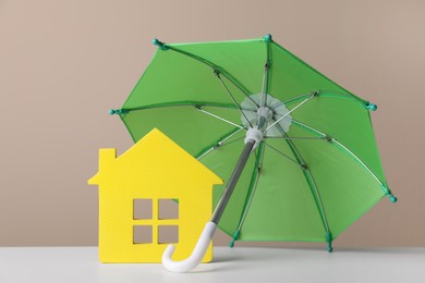 Photo of Small umbrella and house figure on white table