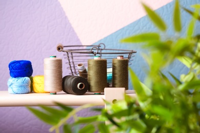 Photo of Metal basket with color sewing threads on table