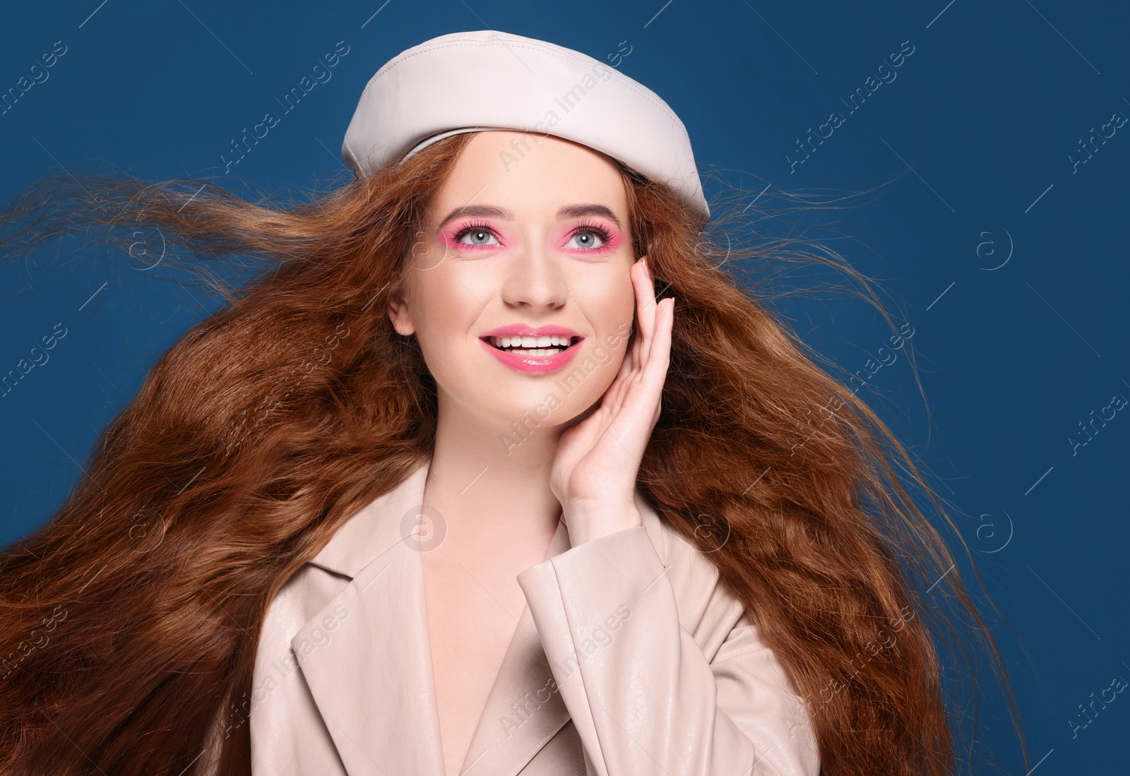 Photo of Portrait of beautiful happy woman with makeup posing on blue background