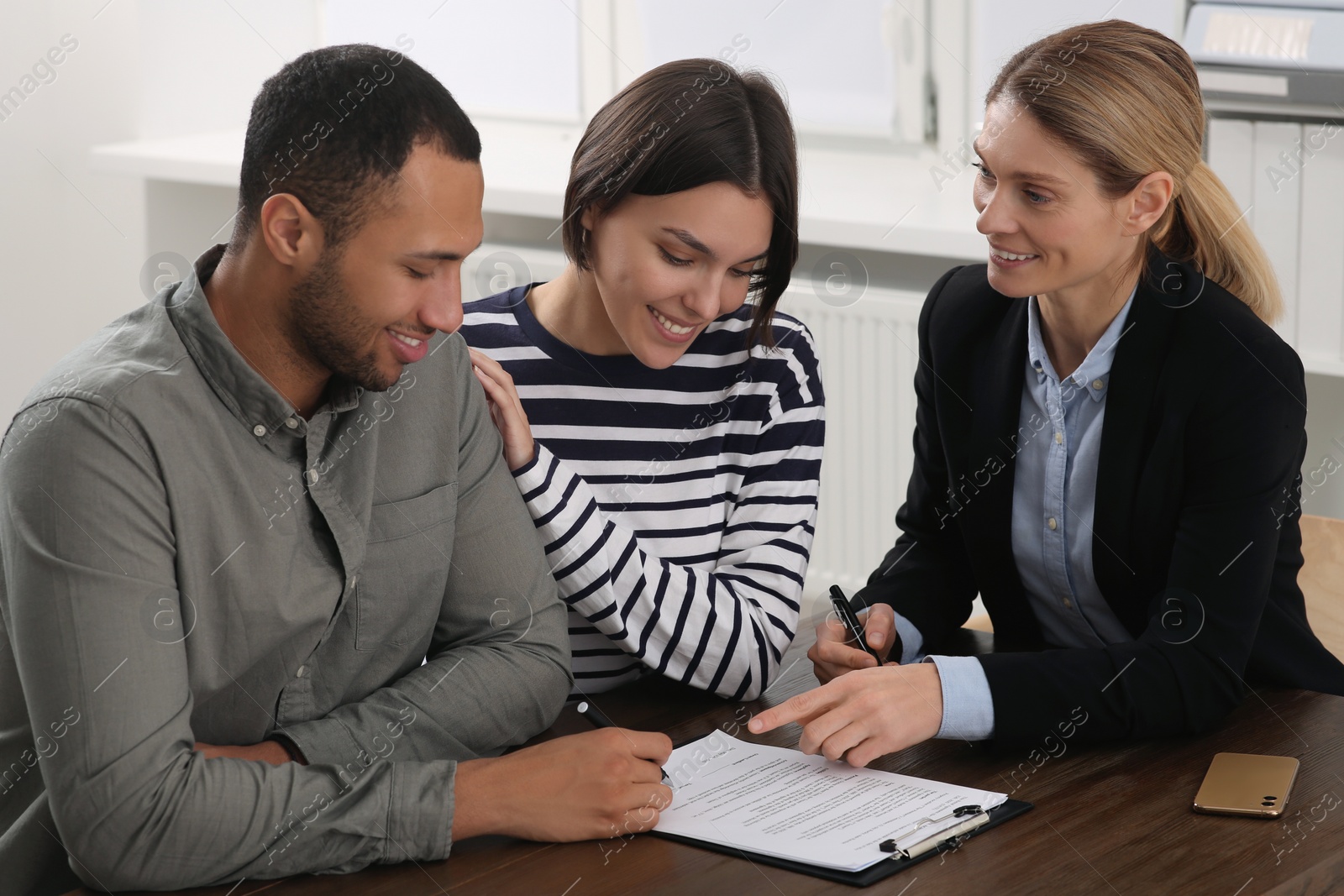 Photo of Professional notary helping couple with paperwork in office