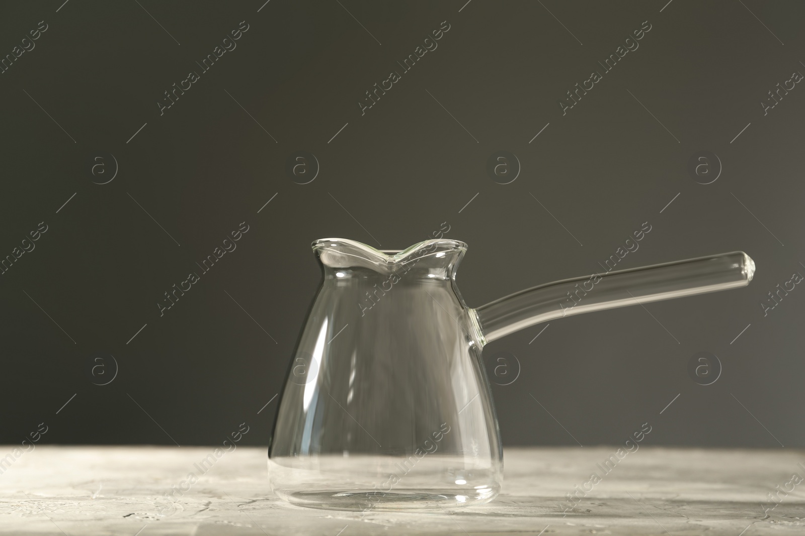 Photo of Empty glass turkish coffee pot on table against grey background