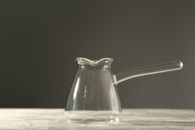 Empty glass turkish coffee pot on table against grey background