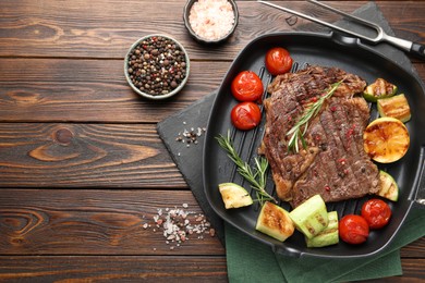 Delicious grilled beef steak and vegetables served on wooden table, flat lay. Space for text