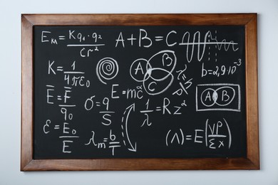 Photo of Blackboard with different physical formulas written with chalk on white wall