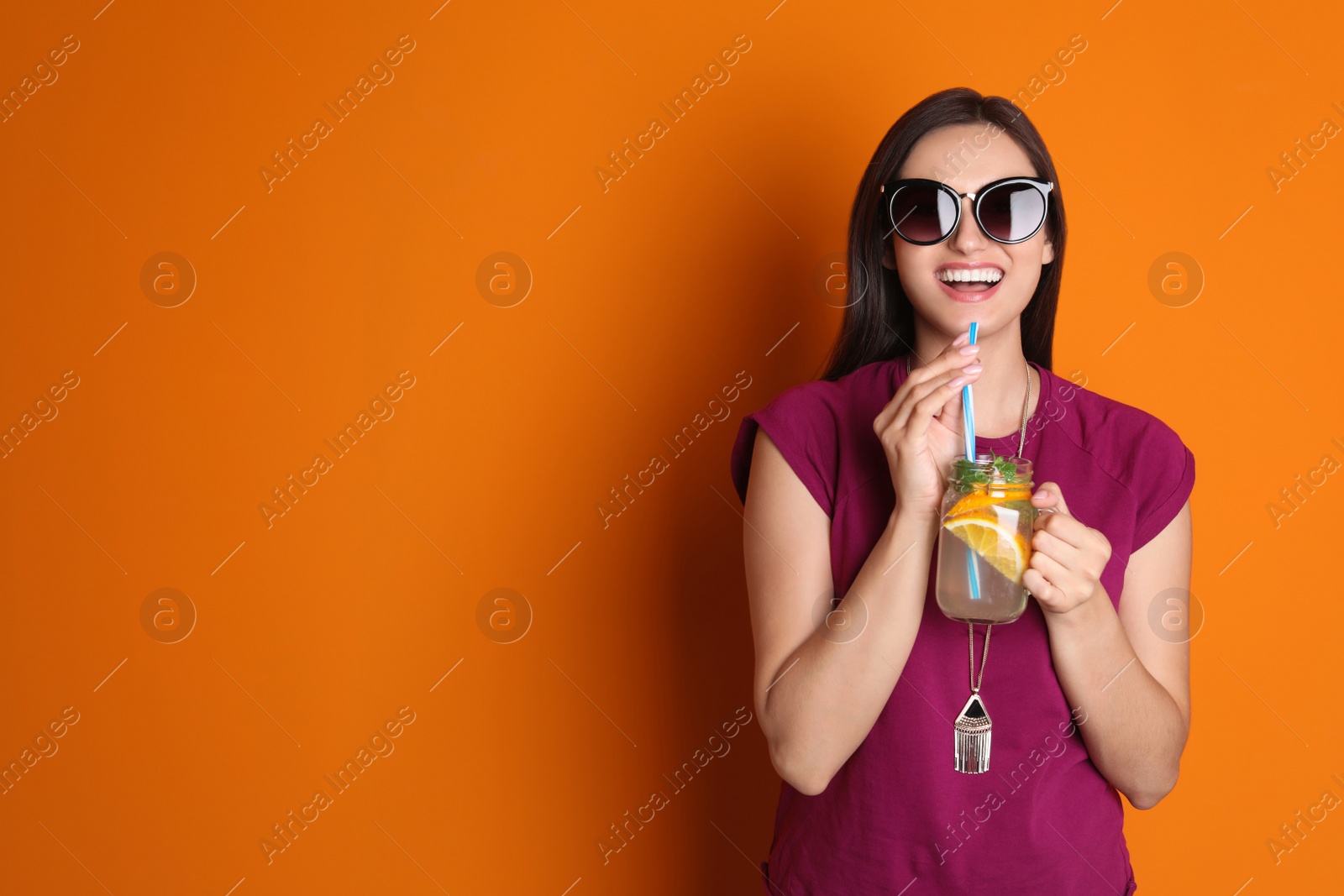 Photo of Young woman with mason jar of tasty lemonade on color background. Natural detox drink