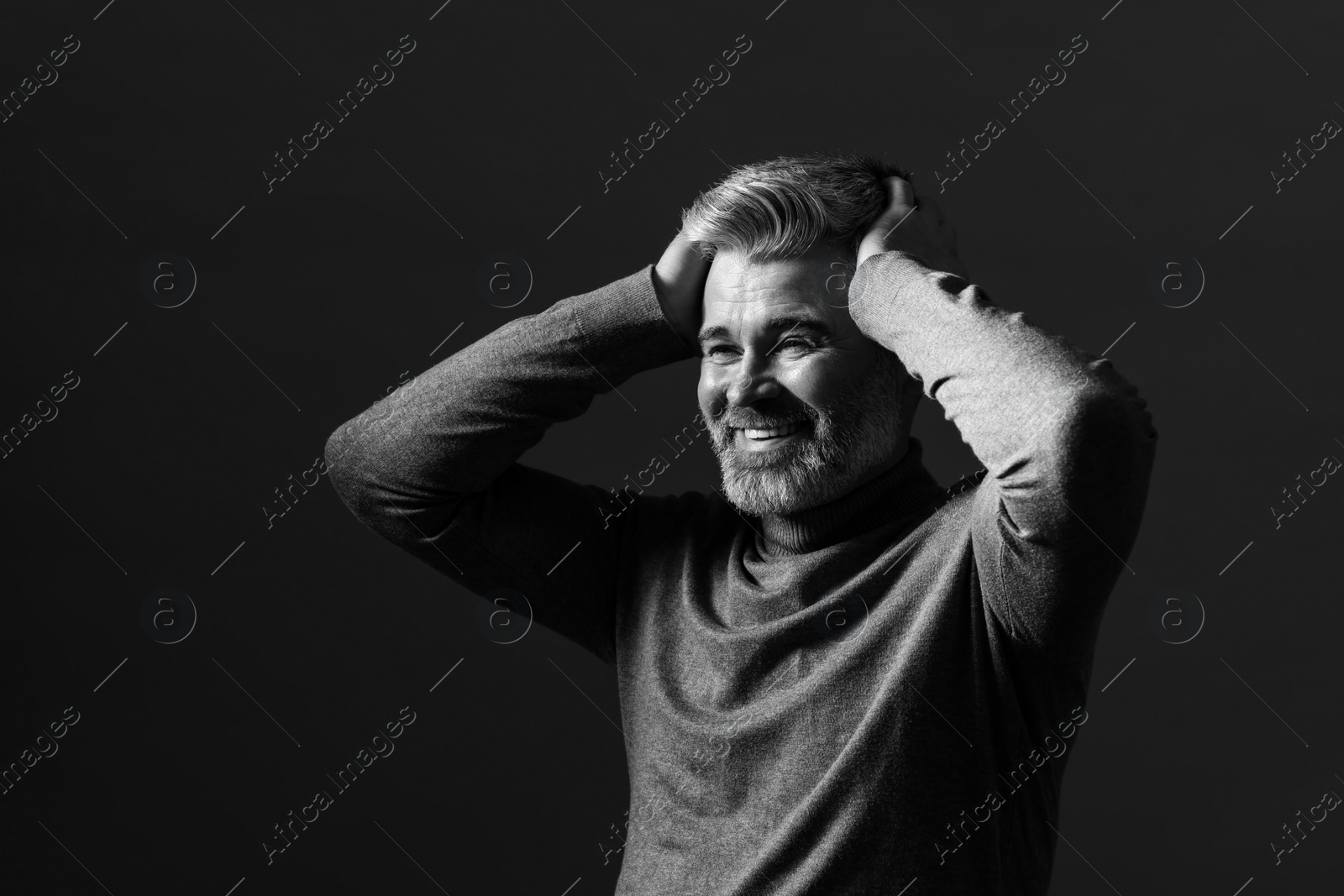 Photo of Portrait of smiling man on dark background. Black and white effect