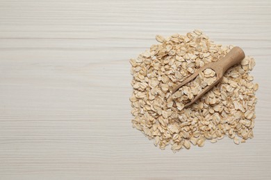 Scoop with oatmeal on white wooden table, top view. Space for text