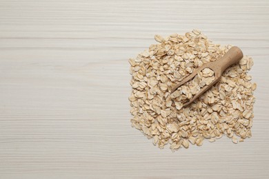 Photo of Scoop with oatmeal on white wooden table, top view. Space for text