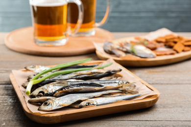 Photo of Tasty dried fish with fresh onion on wooden table